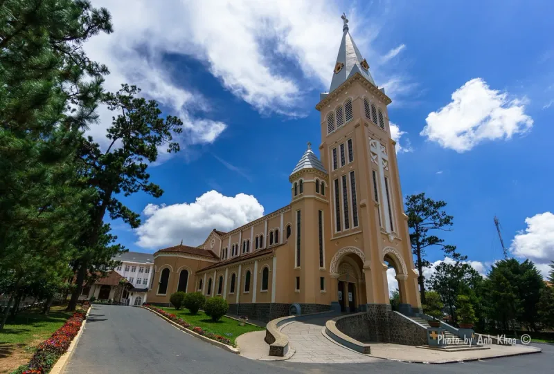 The yellow St Nicholas Cathedral in Da Lat, its clock tower against a blue sky