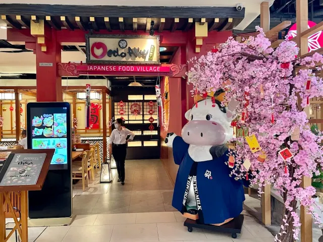 An indoor area in Japanese style with a red gate, artificial pink blossom and a mascot statue