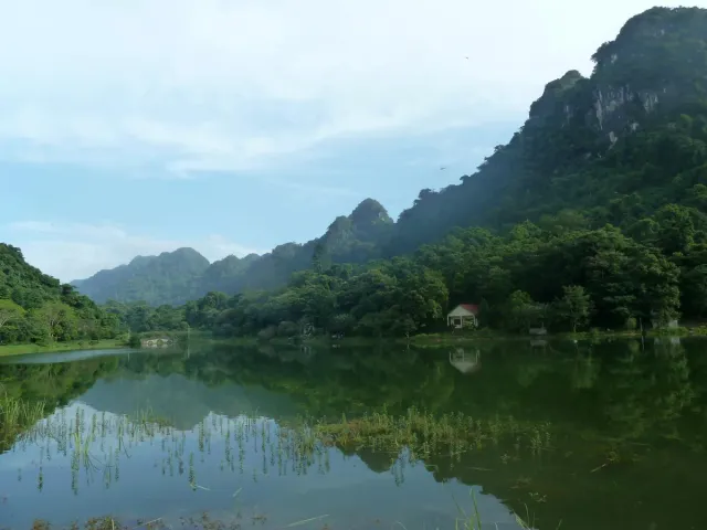 A calm green lake surrounded by tropical forest cliffs