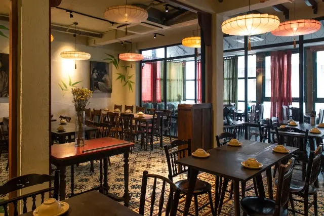 An indoor hall with paper lamps, dark wooden tables and a patterned tile floor