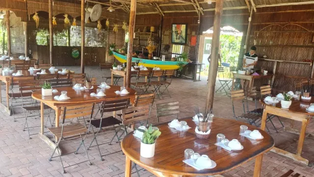 An open wooden dining hall with round tables set with white dishes