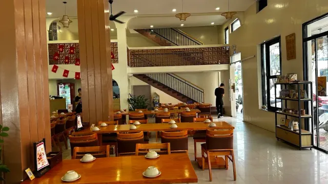A two level hall with a staircase, orange columns and wooden tables set with white bowls