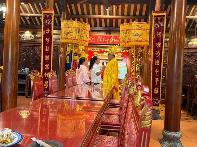 An ornate hall with carved red and gold chairs, wooden pillars and a long glossy table