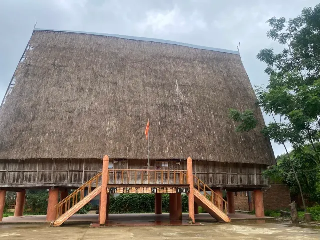 A communal stilt house with a very steep thatched roof and two wooden staircases