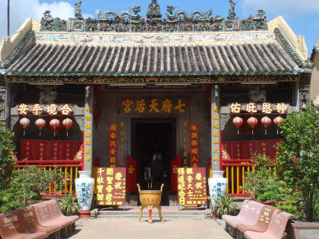 The facade of a Chinese temple with red lanterns and gilded inscriptions