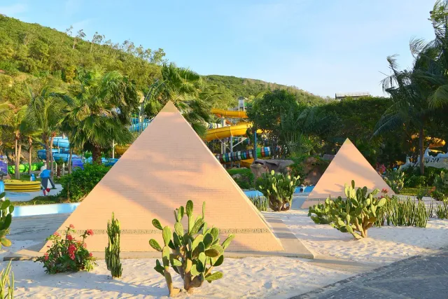 An amusement park with pyramid structures, pools and palm trees