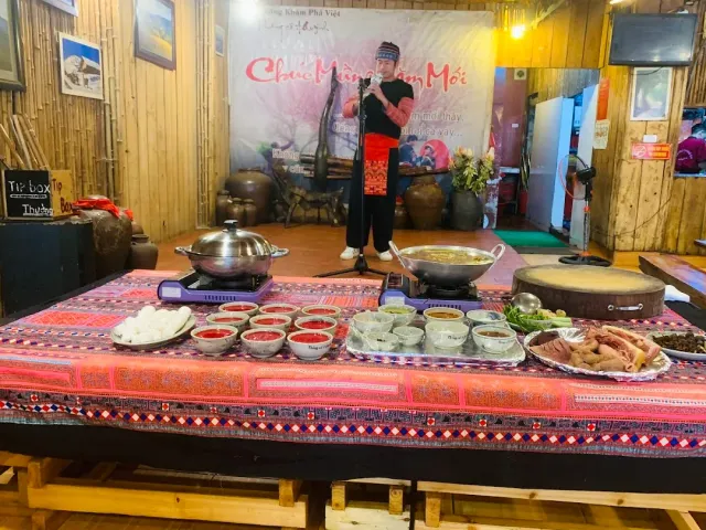 A low table covered with embroidered cloth holding pots on burners and sauce bowls, a singer in traditional dress behind