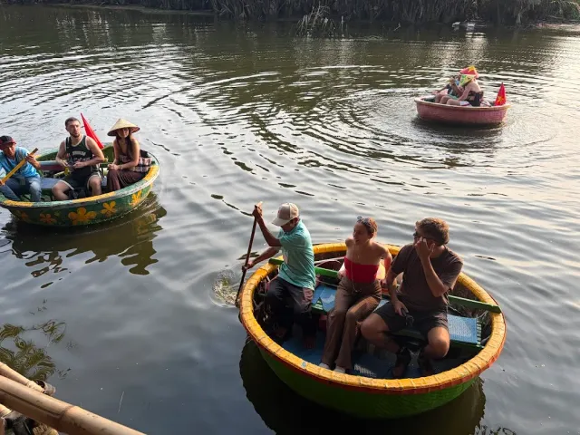 Three round basket boats with passengers and paddlers on brown water