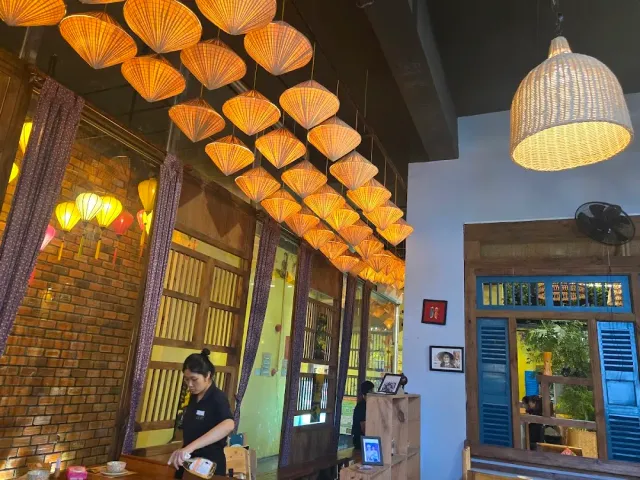 A ceiling lined with rows of woven conical hat shaped lampshades, a brick wall and blue shutters