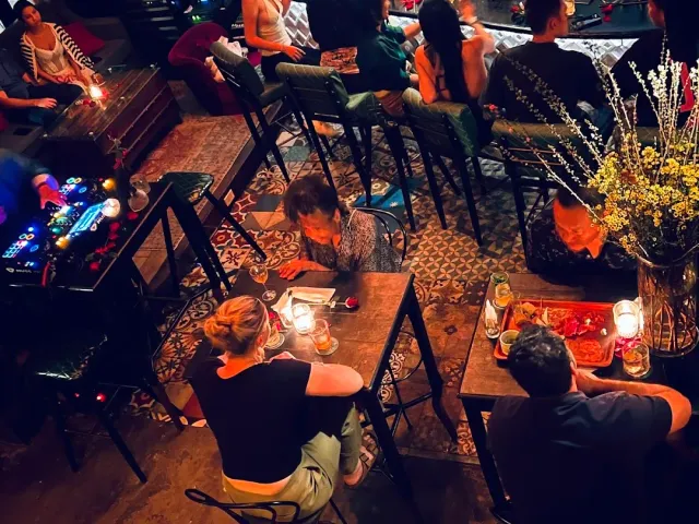 A view from above of a patterned tile floor, tables with candles and guests in red lighting