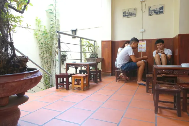 The inside of a plain cafe with low wooden tables and a tiled floor