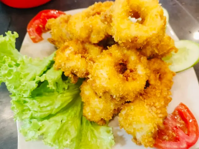 Fried squid rings in crisp batter beside lettuce leaves and tomato slices
