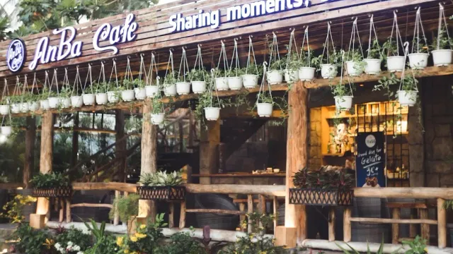 A facade with rows of hanging white pots, rough wooden posts and wicker chairs inside