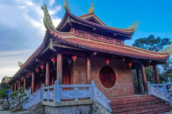 A brick building with a curved tiled roof, red lanterns and white stone steps