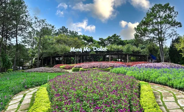 Terraced flower beds in purple and pink, a stone path and a wooden pergola among pines
