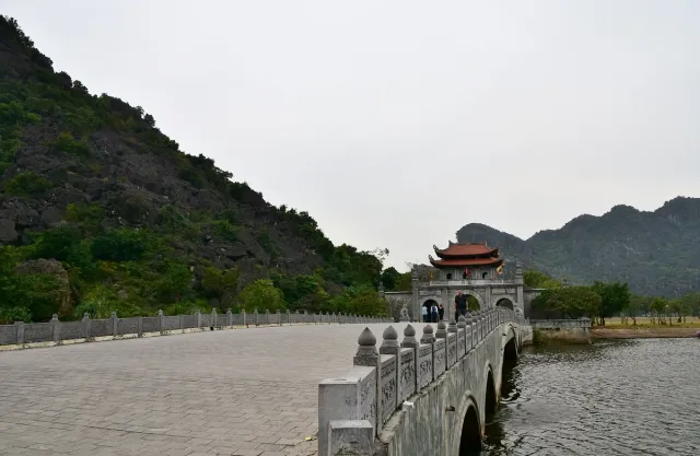 A stone bridge with a carved balustrade leading to the gate of an ancient complex