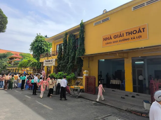 A yellow temple building with a crowd of worshippers in the square before it