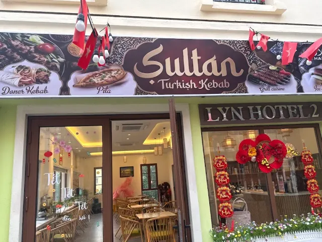 A shopfront with a printed banner of meat dishes, red bunting and wooden seating inside