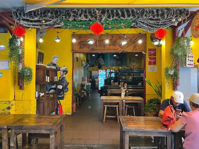 An open front on a yellow wall with a mural, red decorations and wooden tables