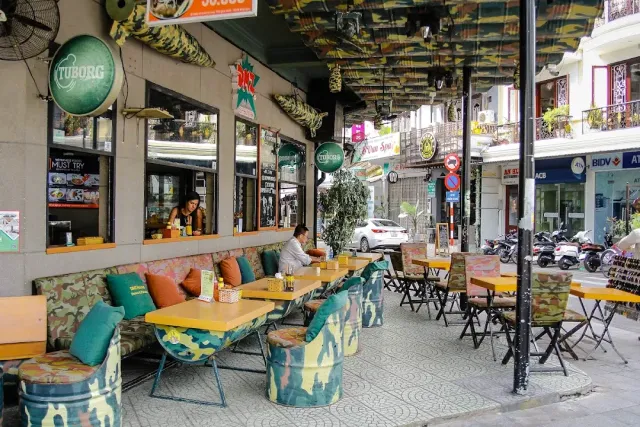 Sidewalk seating with camouflage print stools, yellow tables and a busy street behind