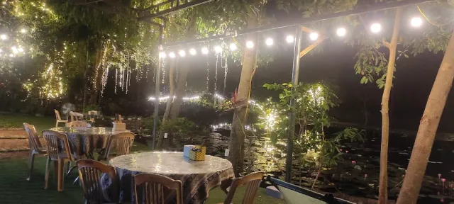 An evening garden with strings of bulbs, round tables and lit trees all around