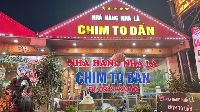 A restaurant front lit at night with a red triangular roof and large signs