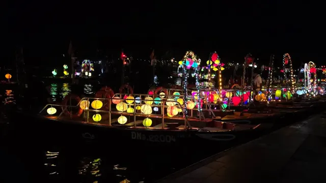Wooden boats moored at night, loaded with glowing colorful lanterns and reflections in the water