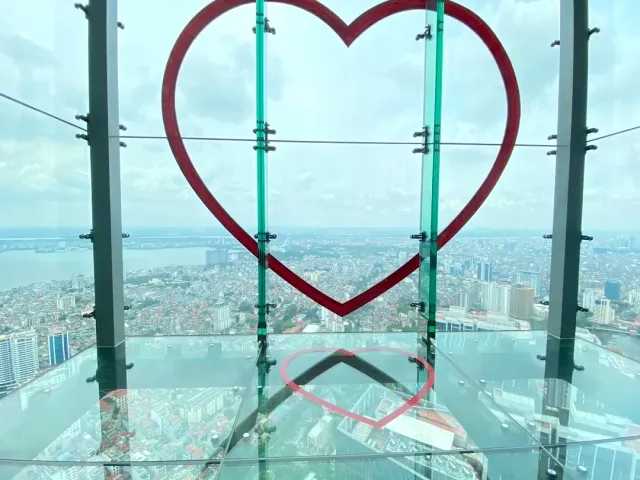 A glass floor with a large red heart frame, and the city seen far below