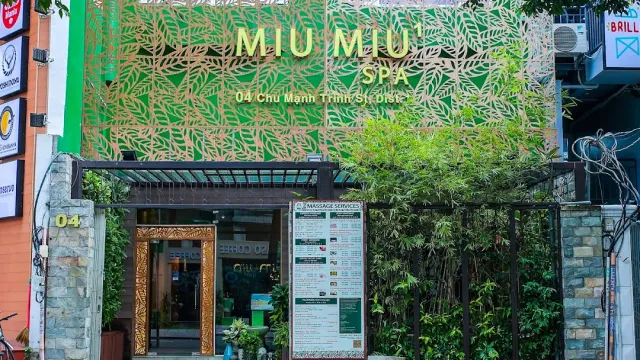 A shop front with a green leaf patterned metal screen, a glass entrance and a services board