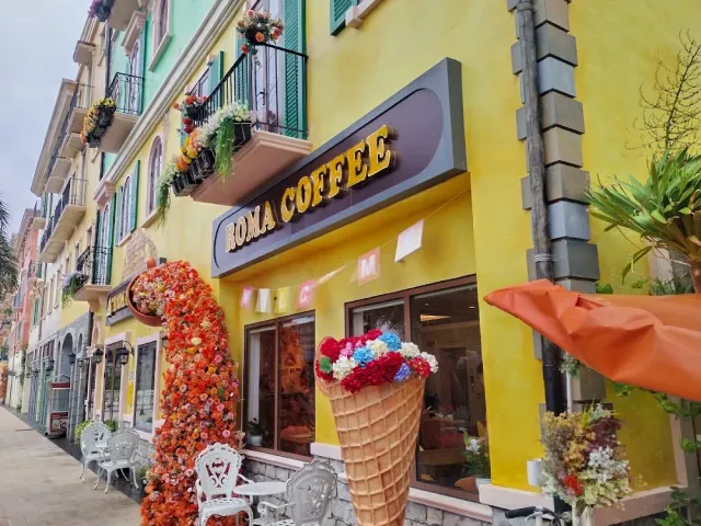 A yellow Mediterranean style facade with a cascade of artificial flowers and a giant ice cream cone