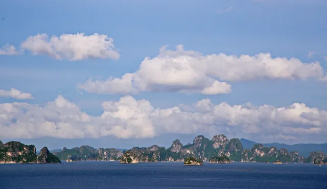 Green limestone islands scattered across calm water under a clear sky