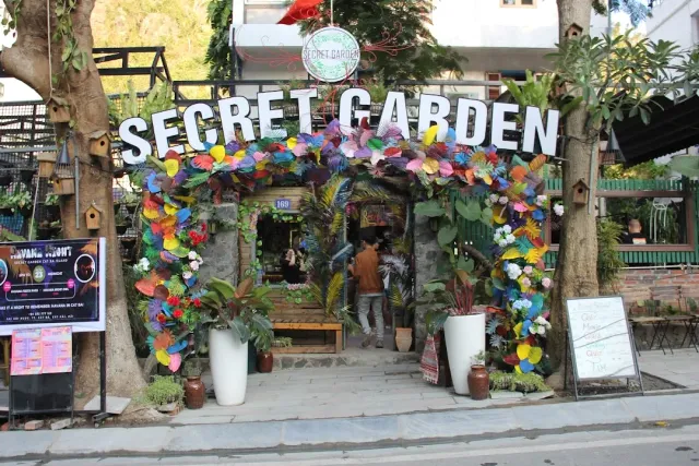An entrance decorated with colorful artificial leaves, large white letters and birdhouses on the tree