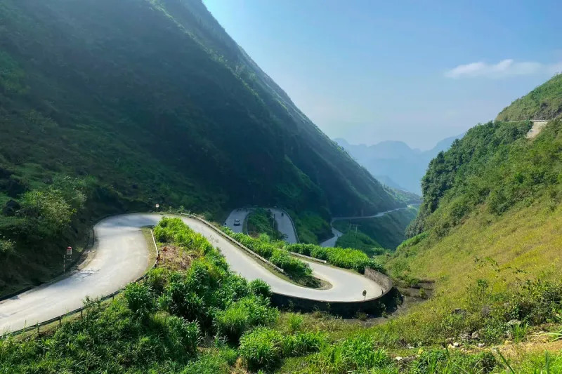 The winding road of Tham Ma pass between green slopes