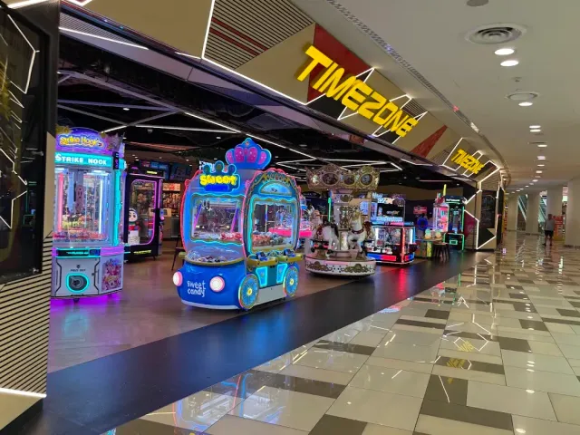 A mall corridor with a games zone, claw machines and a carousel on a polished floor