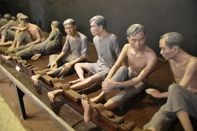 A display of prisoner figures in a row of leg irons