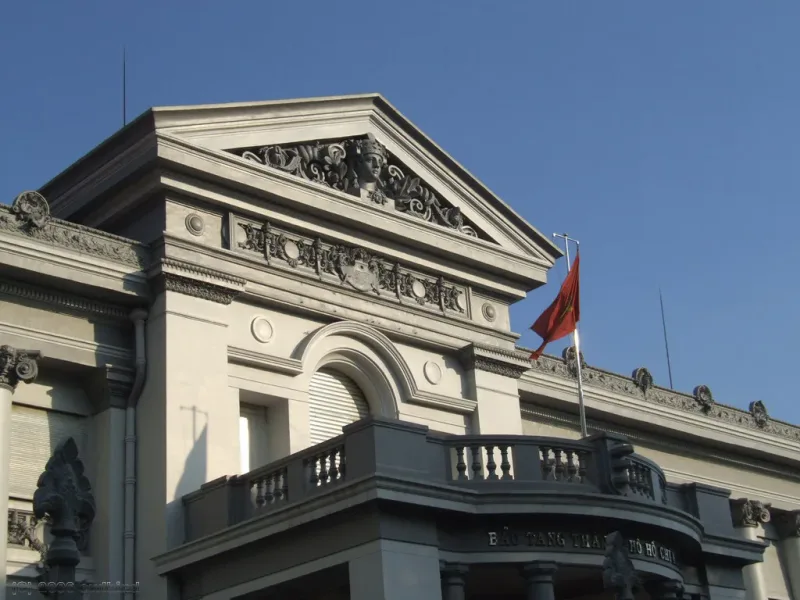 The facade of the Ho Chi Minh City Museum, a colonial building flying the Vietnamese flag
