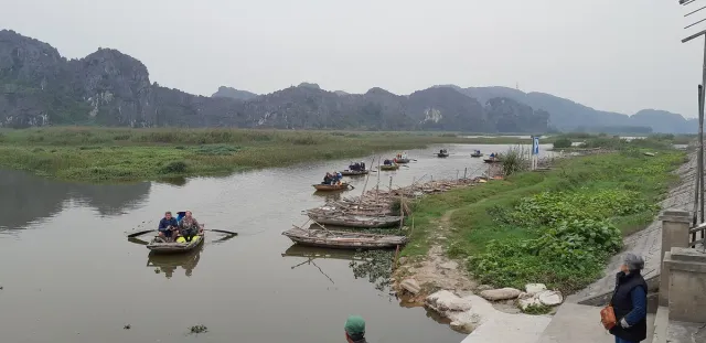 A shallow wetland with small rowing boats below limestone cliffs