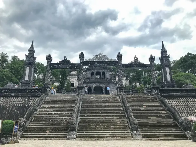 A broad stone staircase rising to an ornate tomb building on a slope