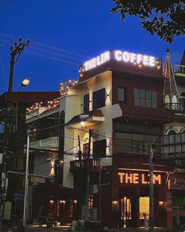 A corner building at dusk with illuminated letters on the roof and a golden lit facade
