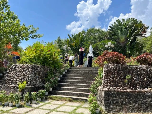 Stone steps rising between pebble faced walls to a white statue at the top