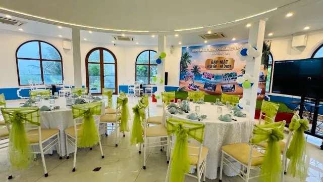 An event hall with round tables, chairs wrapped in green sashes and balloons