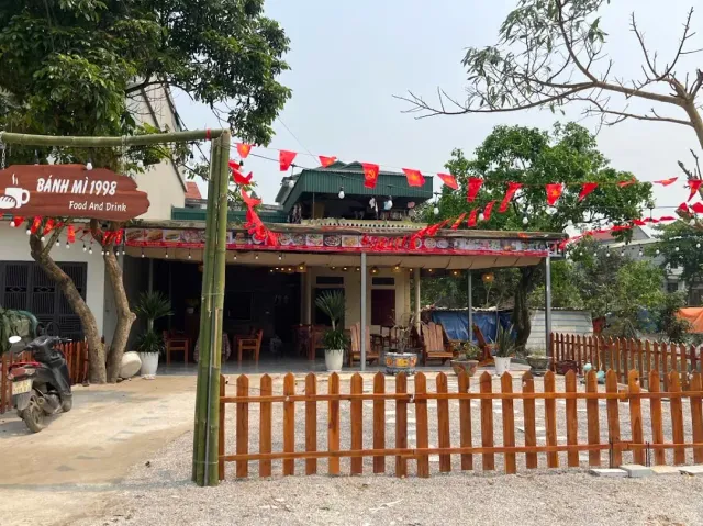 A covered seating yard with red bunting strings, a low wooden fence and a parked scooter