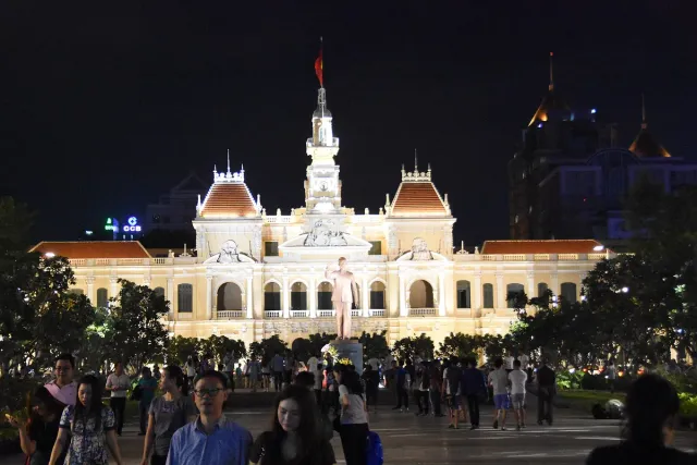 A pedestrian street lit at night with a floodlit civic building at the far end