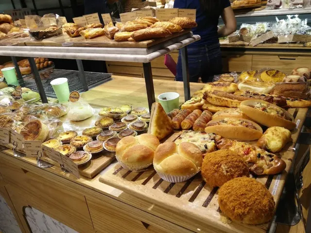 A bakery counter piled with breads, baguettes and individual pastries on wooden trays