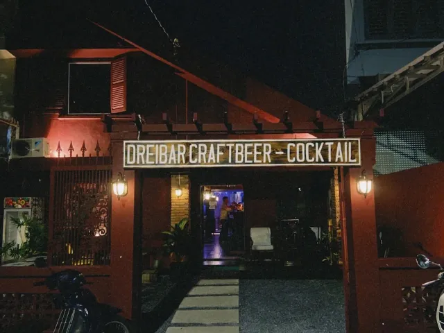 A night entrance to a red house with a wide lit sign above the gate and lanterns on both sides