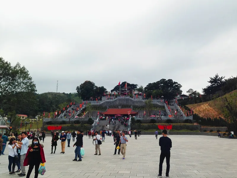 Cua Ong Temple on its hill, with flights of steps and red flags, and visitors on the square below