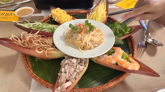 A woven basket with papaya salad, shrimp and crispy noodles in banana flower leaves