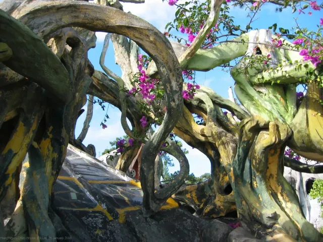 An organic curved building shaped like tree trunks with purple flowers