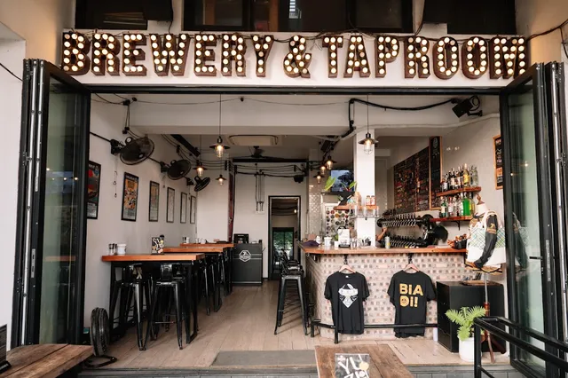 An open storefront with a light bulb sign above, a bar with beer taps and high stools
