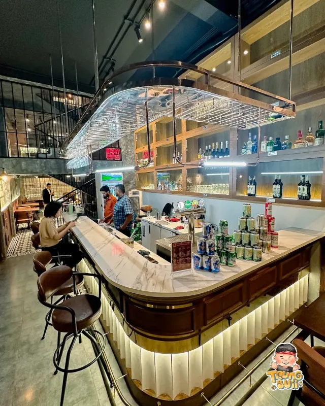 A marble bar counter with bottle shelves, beer cans and high stools in a two story space
